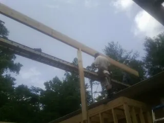 Carpenter setting a ridge beam over a new addition frame — Ice Dam Removal by Roofing Brothers in Saint Joe