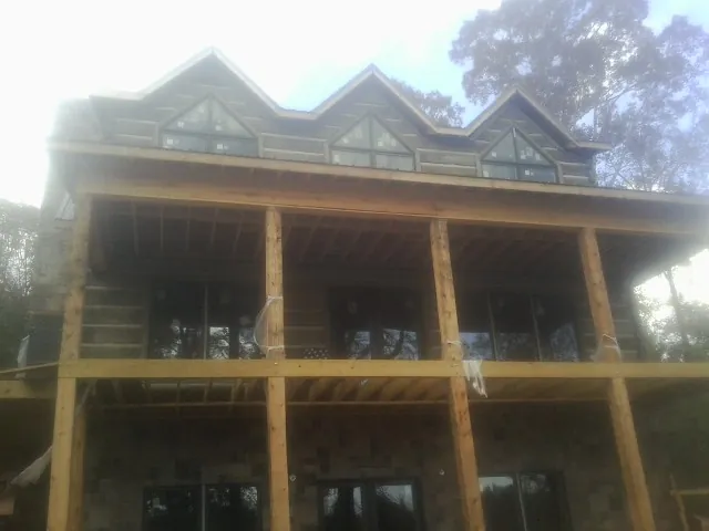 Dormers and porch framing on a large log home under construction — Roof Coating work by our crew in Saint Joe
