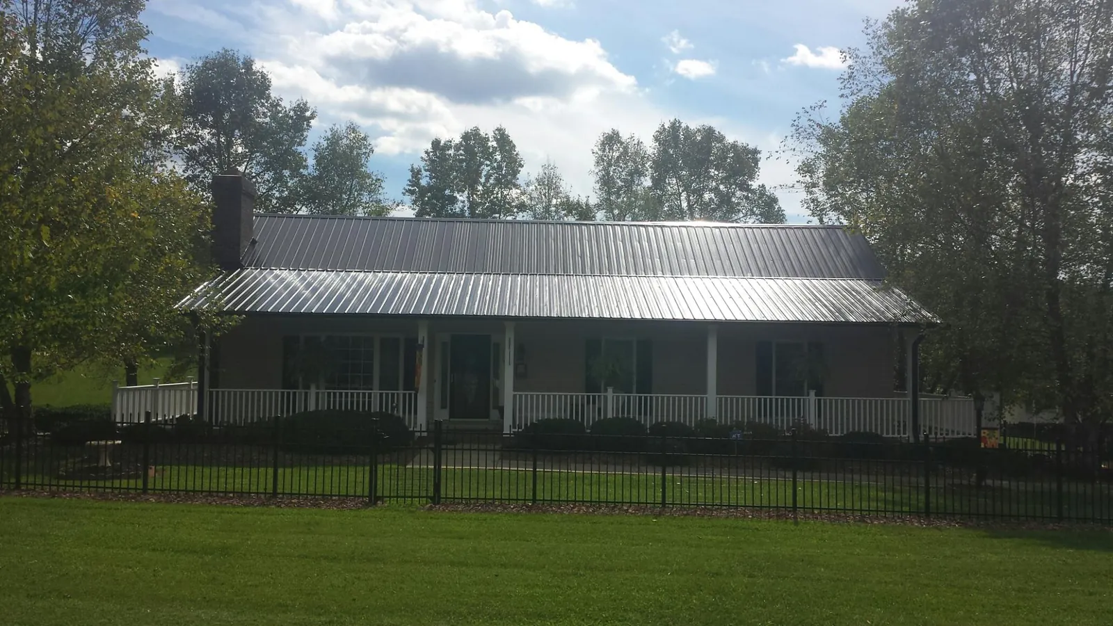 Gray metal roof on a brick ranch with a full width front porch — Gutter Guard Installation work by our crew in Saint Joe