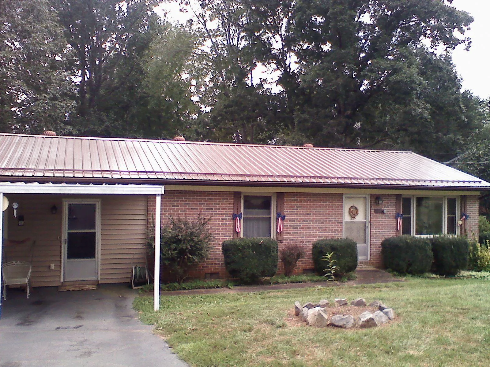 Bronze metal roof and carport on a brick ranch home — Roof Repair work by our crew in Saint Joe