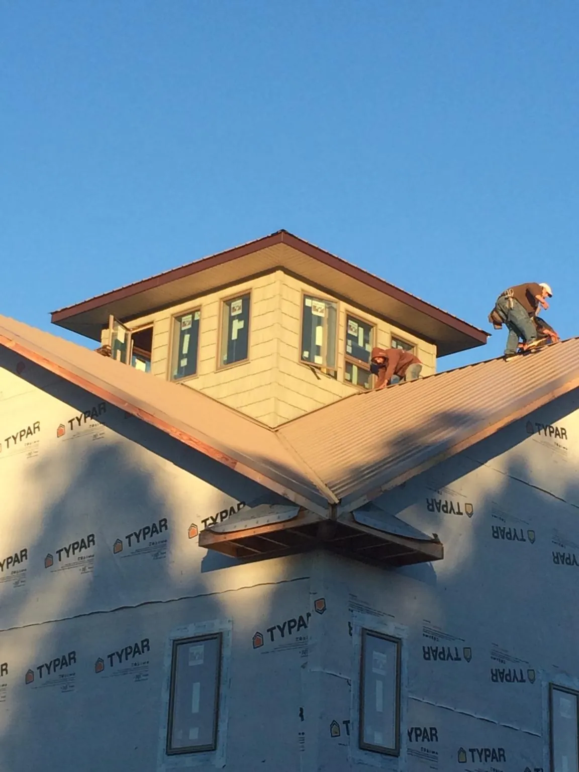 Roofers working around a rooftop cupola on a new metal roof at sunset — Roof Waterproofing in Saint Joe by Roofing Brothers